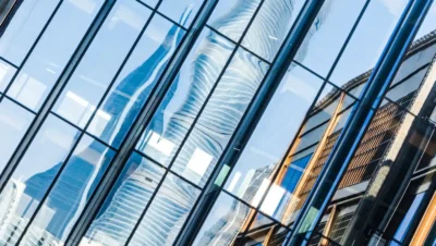 Detalhes da fachada de uma vidraçaria moderna, exibindo janelas de vidro refletindo edifícios ao redor, ilustrando a diferença entre vidraçaria comum e industrial.